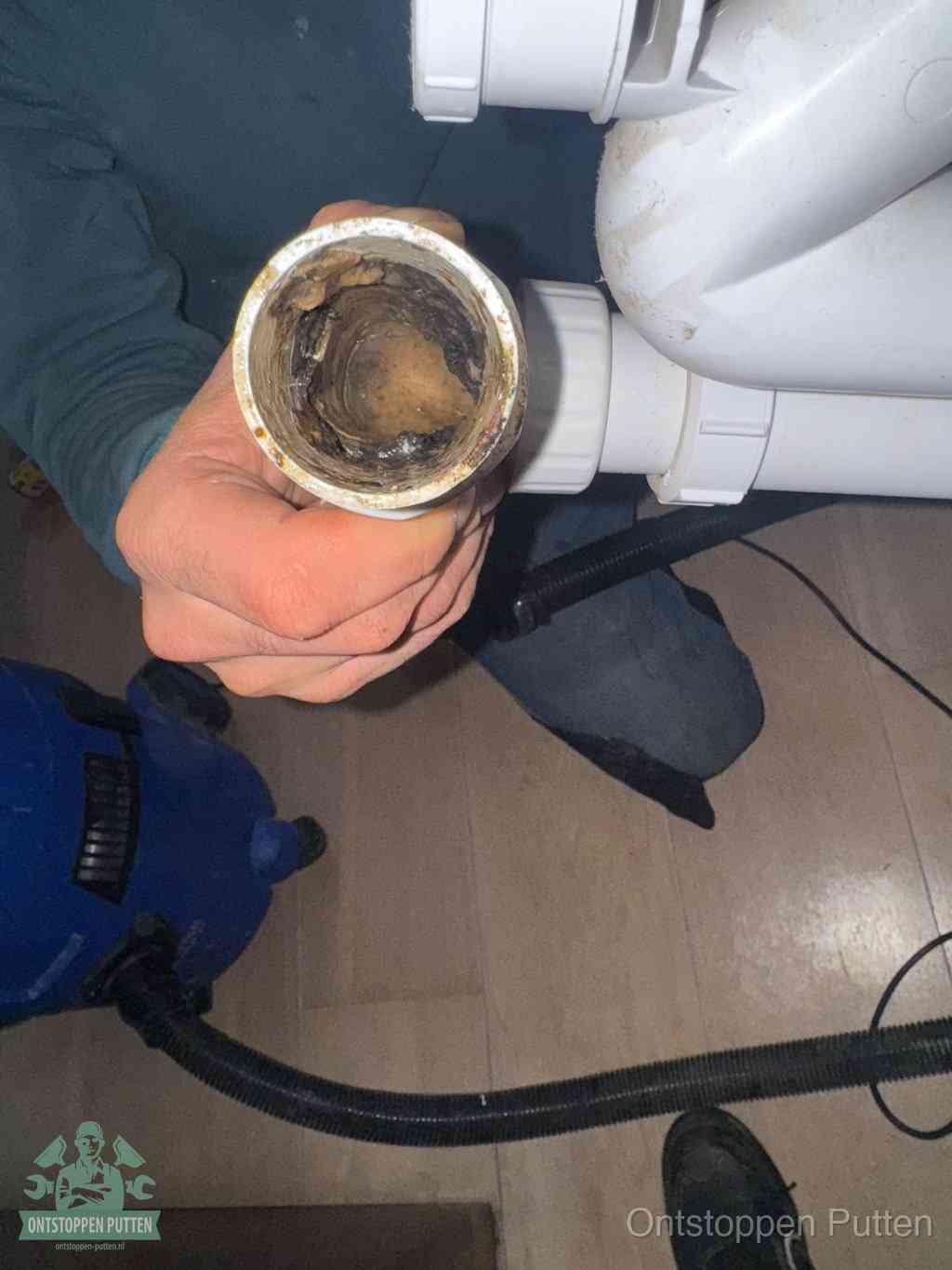 Een losgekoppeld PVC-afvoerbuisstuk dat van binnen volledig is dichtgeslibd met vet en vuil, de meest voorkomende oorzaak van verstoppingen in Putten