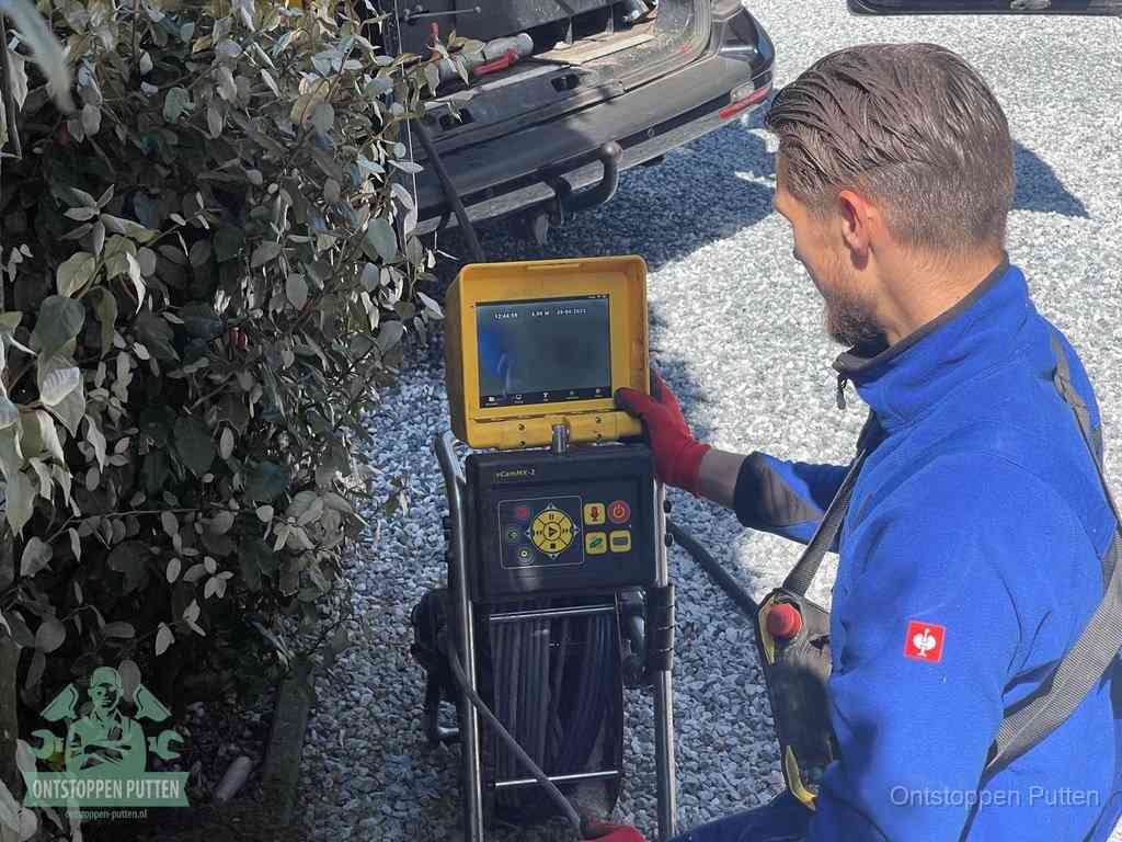 Een monteur bedient een rioolinspectiecamera met monitor en haspel om de verstopping in beeld te brengen in Putten