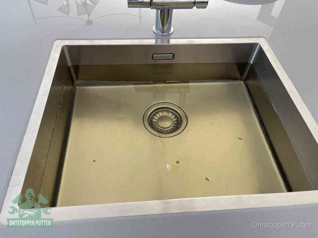 Een RVS spoelbak met stilstaand water dat niet wegloopt, een van de eerste signalen van een beginnende verstopping in Putten