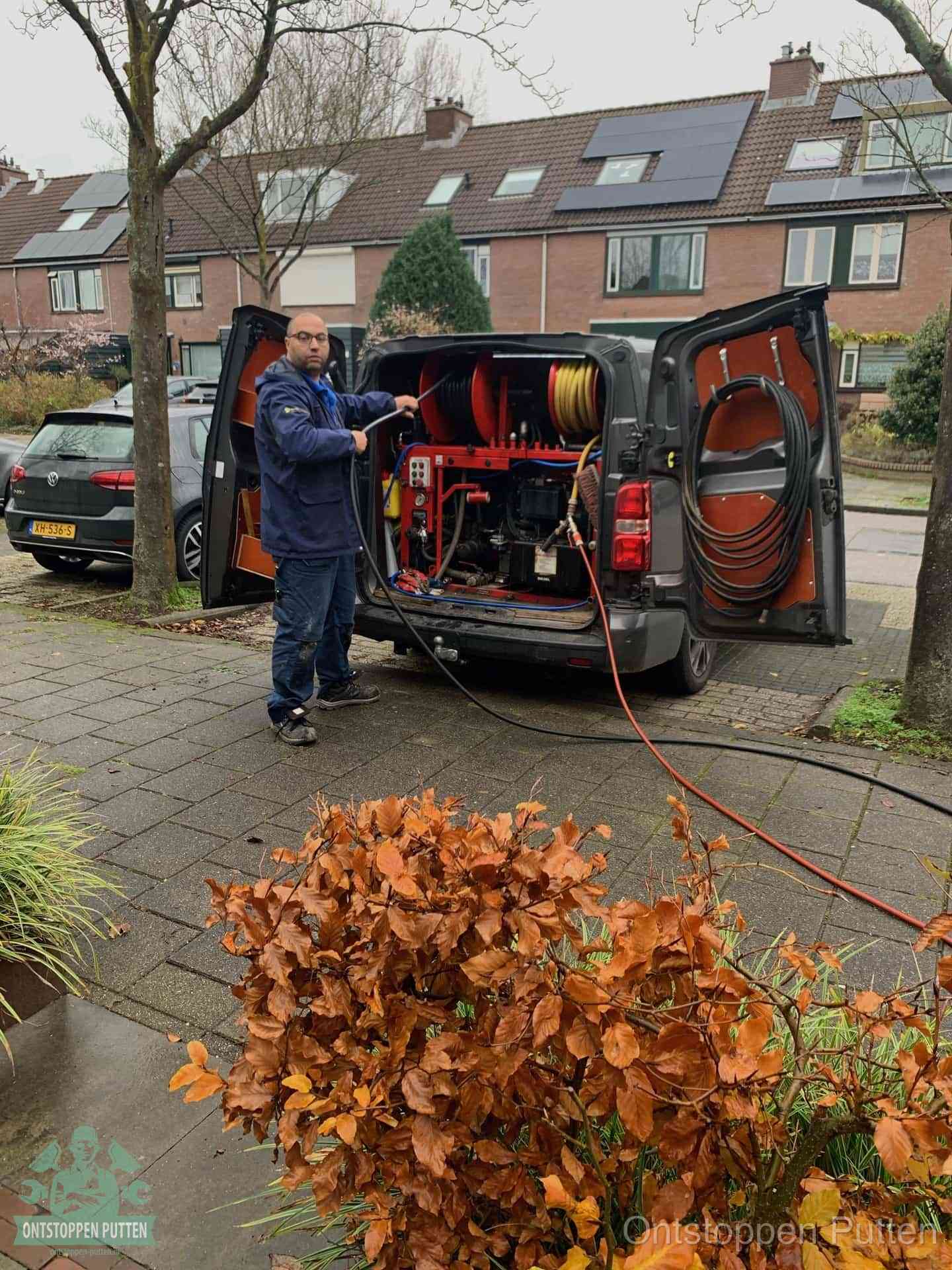 Een monteur staat bij zijn open bestelbus met hogedruk-rioolreinigingsapparatuur, klaar om binnen 30 minuten uit te rukken voor een spoedverstopping in Putten