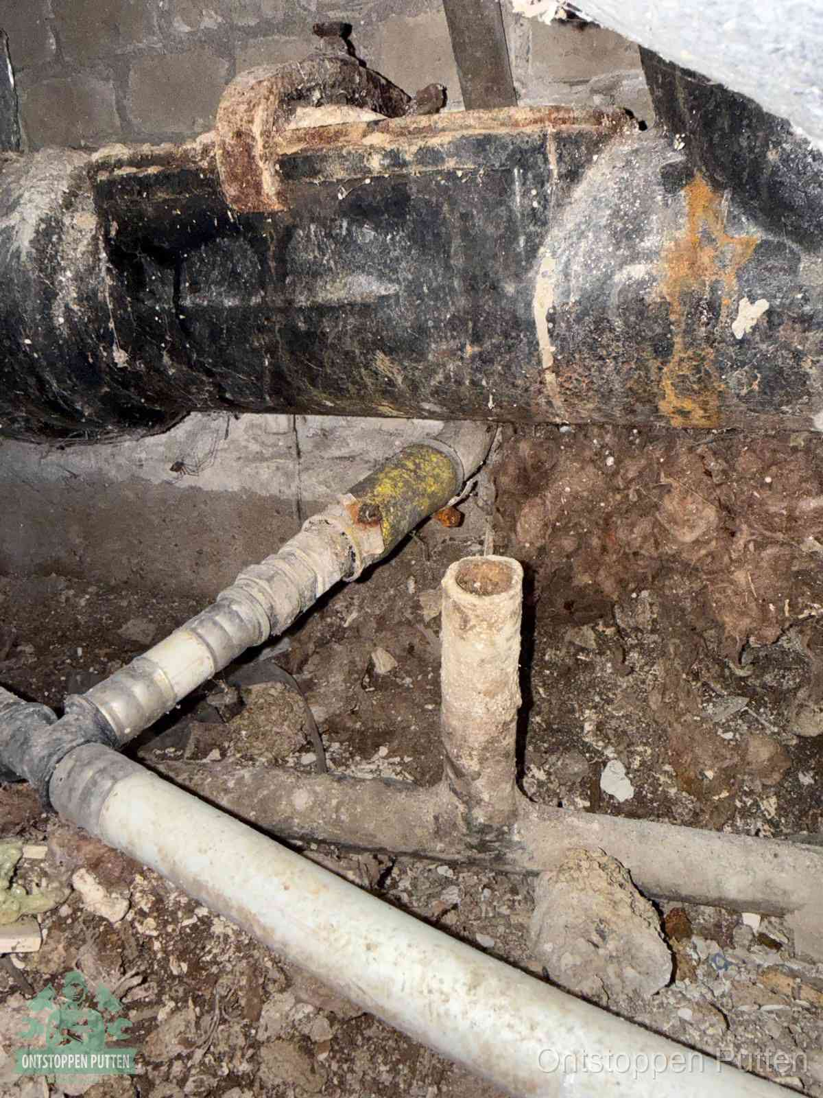 Een oude hoofdrioolbuis met roest- en kalkaanslag in een kruipruimte, oorzaak van terugkerende structurele rioolproblemen in Putten